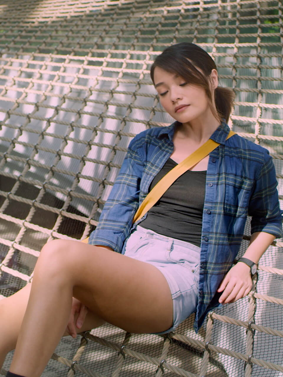 A girl looking downwards and sitting on the ground with legs stretched out